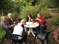 de-leden-die-de-tuin-bij-de-lesstand-onderhouden-even-aan-een-kopje-koffie 