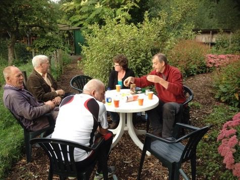 de-leden-die-de-tuin-bij-de-lesstand-onderhouden-even-aan-een-kopje-koffie